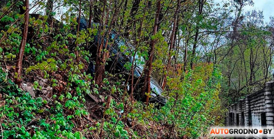В Гродно кто-то хорошо съездил на шоппинг: у ТЦ «Корона» машина выехала с парковки, протаранила забор и застряла на склоне в кустах